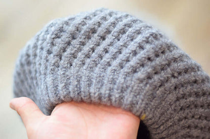 Close-up of a soft, gray knitted Fur Ball Hat showcasing its texture and cozy design.