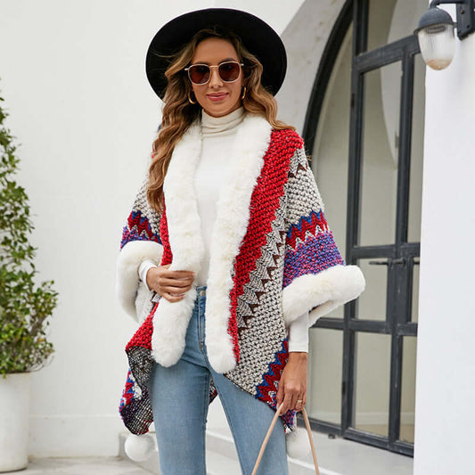 Stylish woman wearing a fur trimmed poncho with colorful patterns, paired with a black hat and sunglasses.