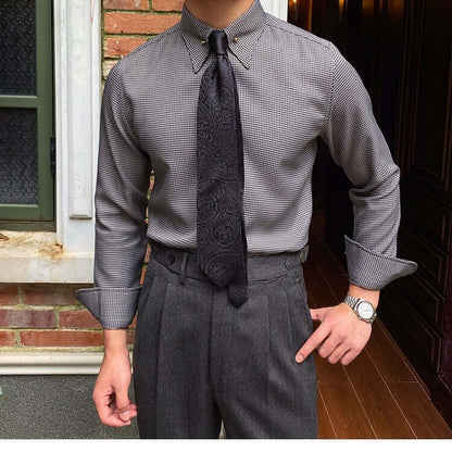 Elegant gentleman wearing a plaid fashion shirt with black tie and gray trousers, showcasing sophisticated style.
