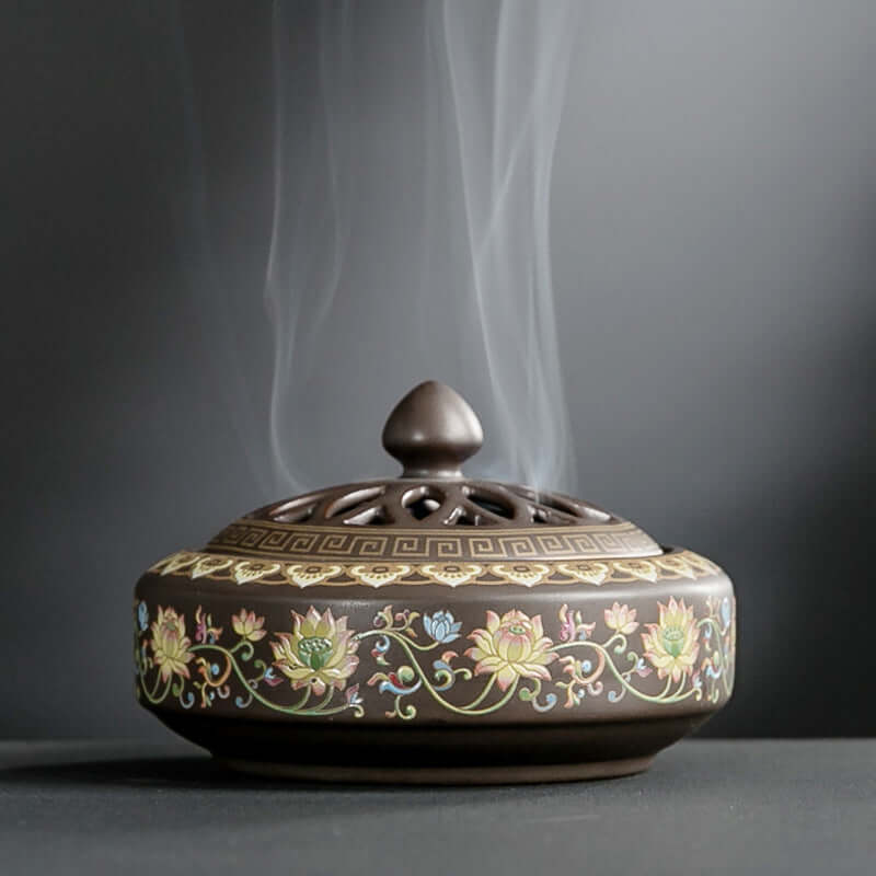 Ceramic incense burner with floral designs releasing aromatic smoke, perfect for tranquility and home decor.