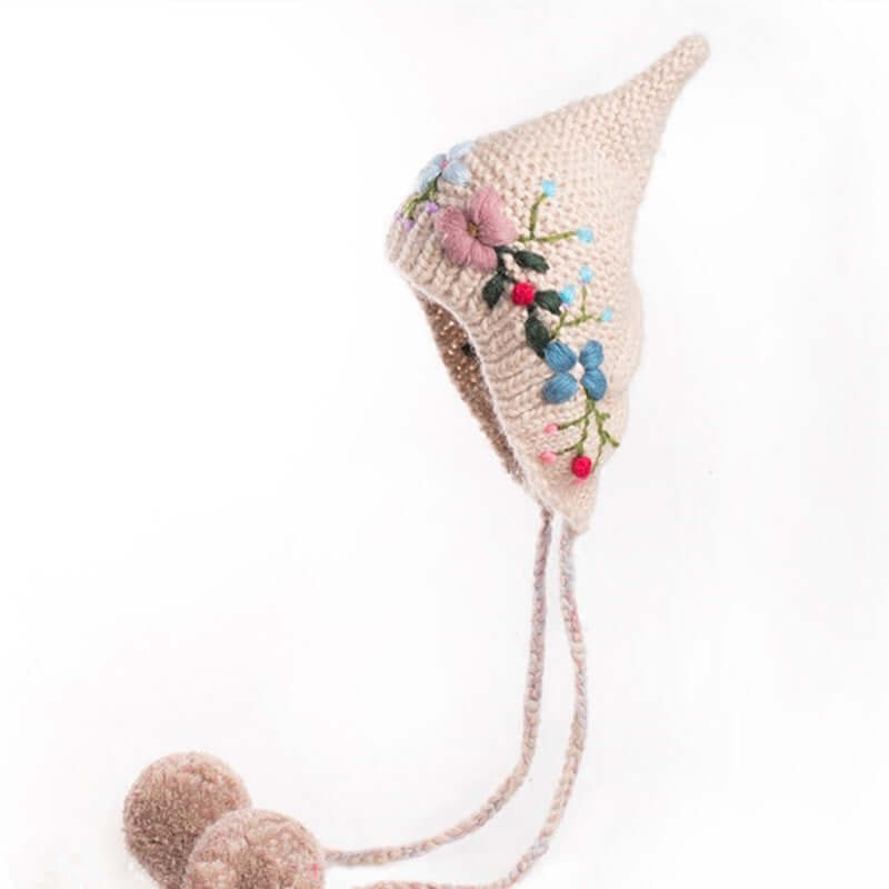 Charming knitted wool hat with floral embroidery and pom-poms, perfect for cozy autumn and winter styling.