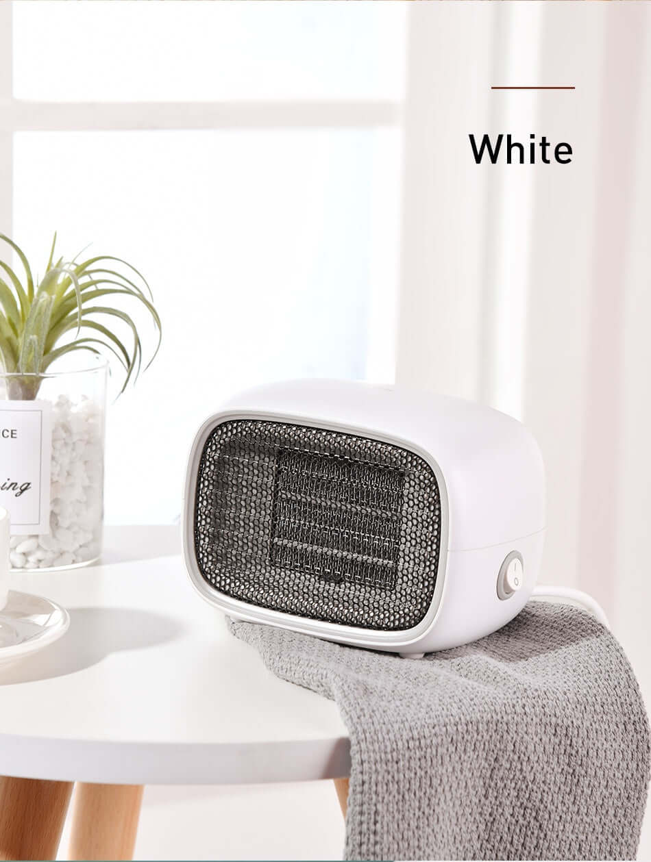 Home Depot Mini Heater on a table with a cozy throw, showcasing its compact design and white finish.