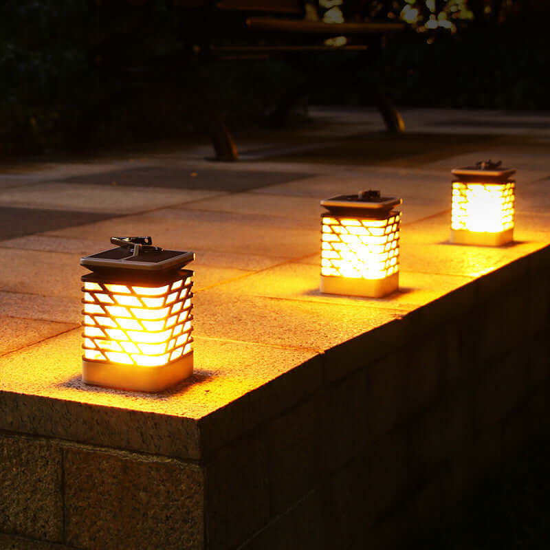 Rectangular lanterns casting a warm glow on a stone patio, perfect for outdoor ambiance and garden parties.