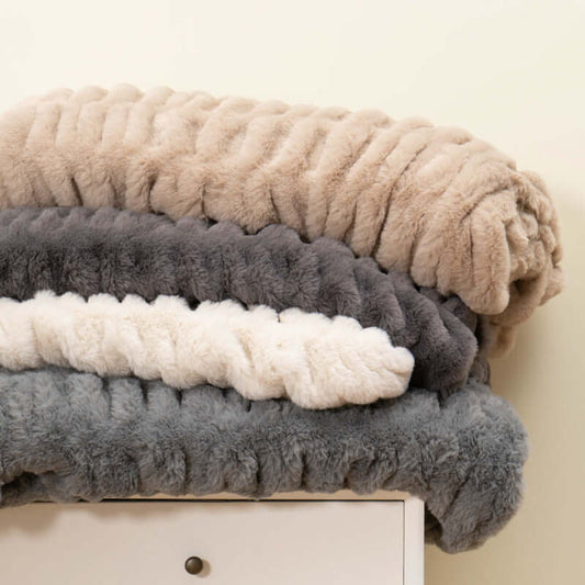 Cozy faux fur pelt blankets stacked in neutral colors, perfect for adding warmth and style to your home decor.
