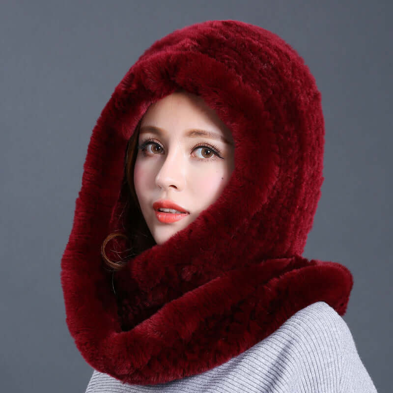 Stylish woman wearing a luxurious burgundy fur hat with scarf for winter warmth and elegance.