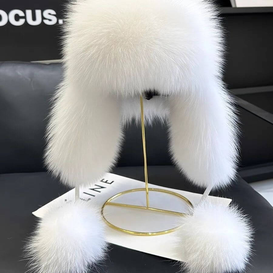 Chic white Ushanka Fur Hat displayed on a stand, showcasing its luxurious fur and stylish design, perfect for winter.
