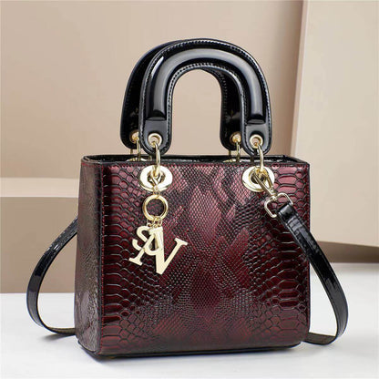 Elegant red and black square handbag with snake-skin pattern and gold accents, featuring a top handle and detachable strap.
