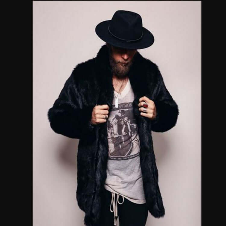 Man wearing a stylish mink-like faux fur coat and black hat, showcasing fashionable winter attire.