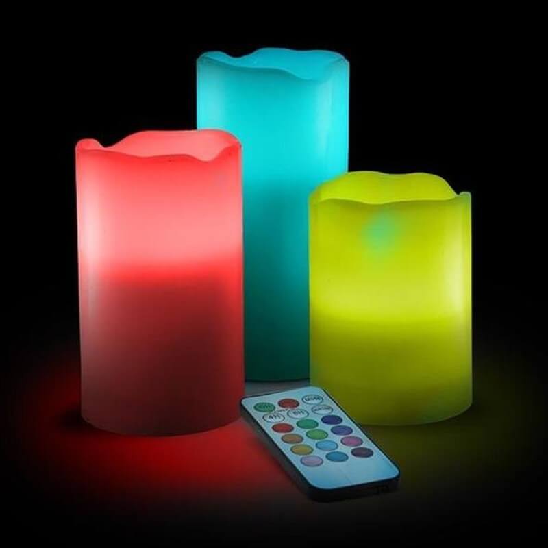 Set of colorful flameless candle stick candles with a remote control against a black background.