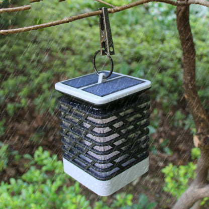 Rectangular lantern hanging outdoors in rain, enhancing garden ambiance with warm glow and modern design.