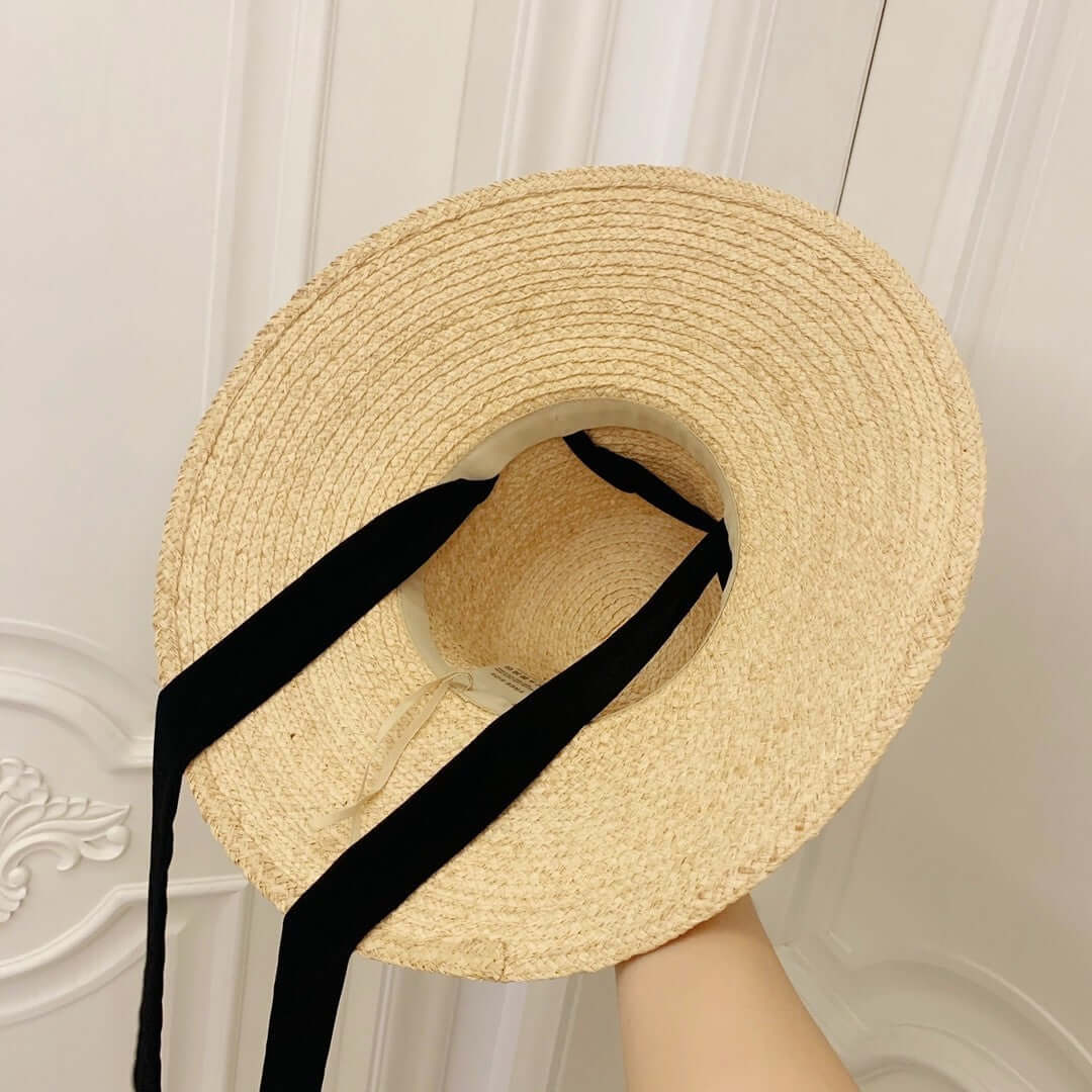 Top view of a Raffia Big Brim Hat showcasing its stylish design and black ribbon straps for a chic summer accessory.