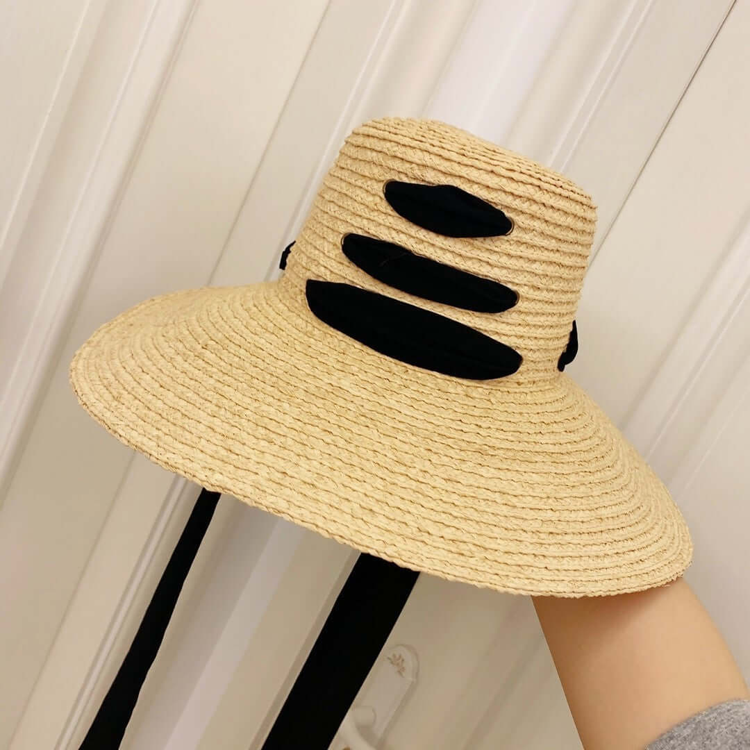 Stylish raffia big brim hat featuring black accents, perfect for summer elegance and sun protection.