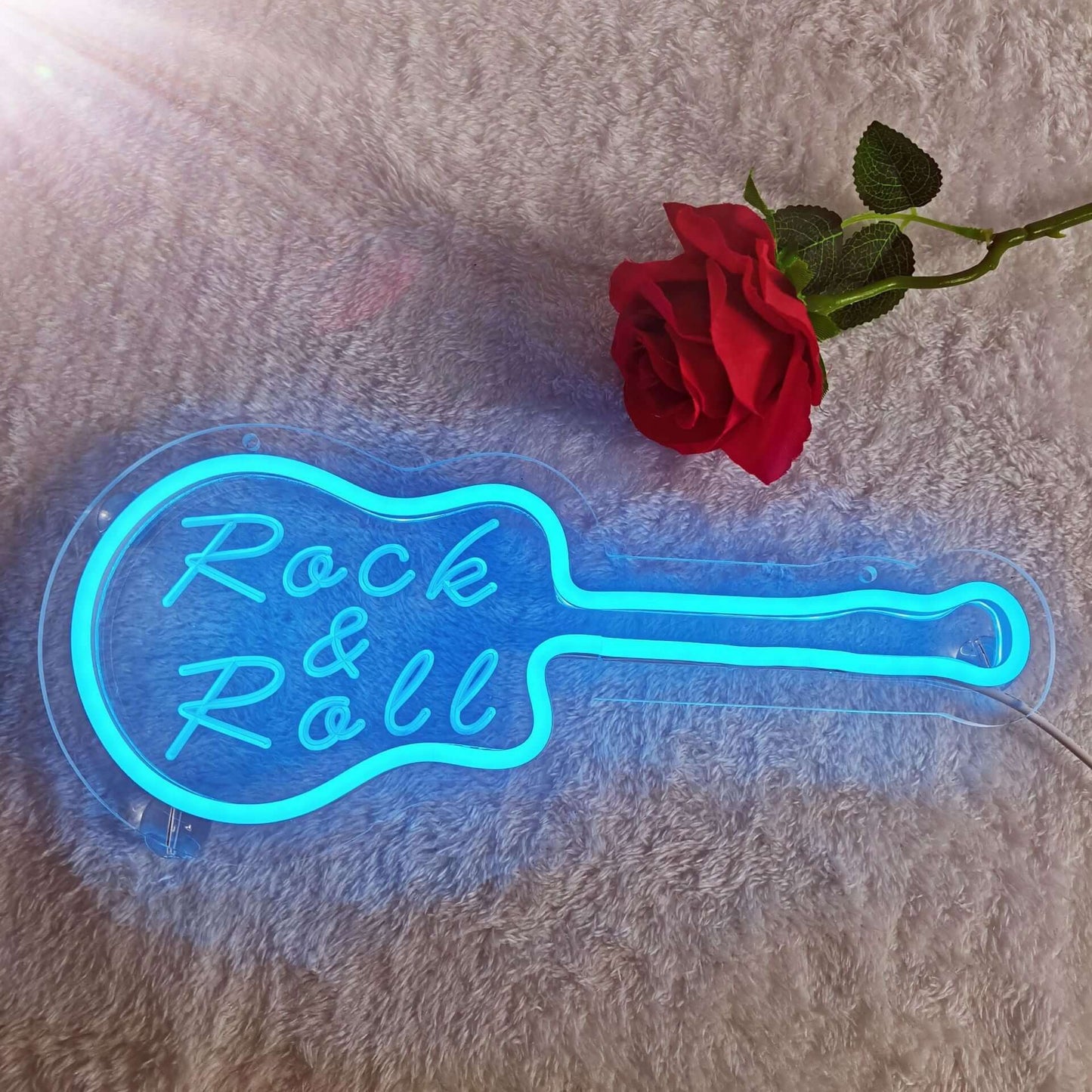 Neon blue 'Rock & Roll' guitar night light with a red rose on a soft background, adding a vibrant touch to home decor.