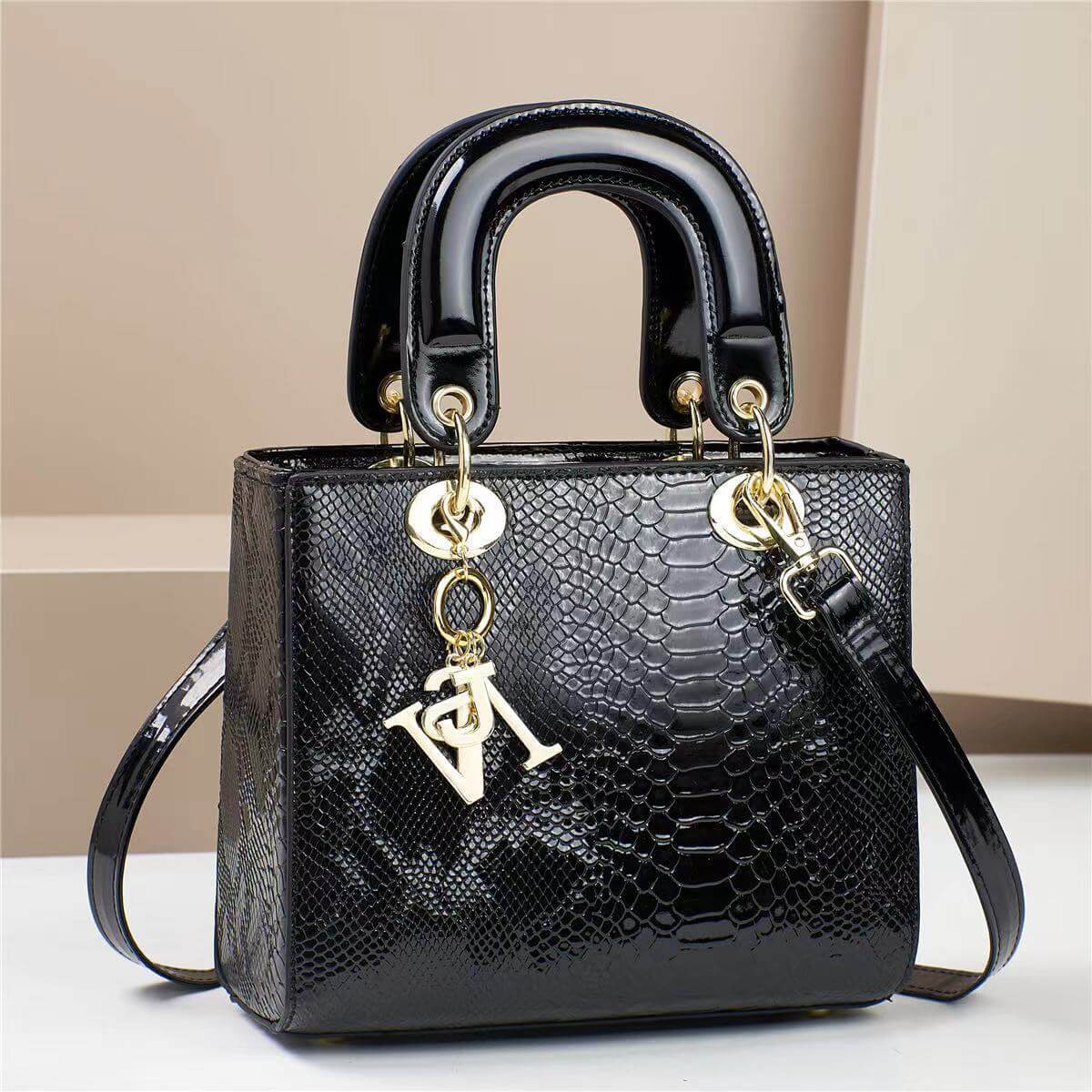 Elegant black handbag with snakeskin texture and gold accents, perfect for sophisticated style and daily use.