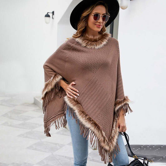 Stylish woman wearing a brown cape sweater with fringes and faux fur trim, perfect for autumn fashion.