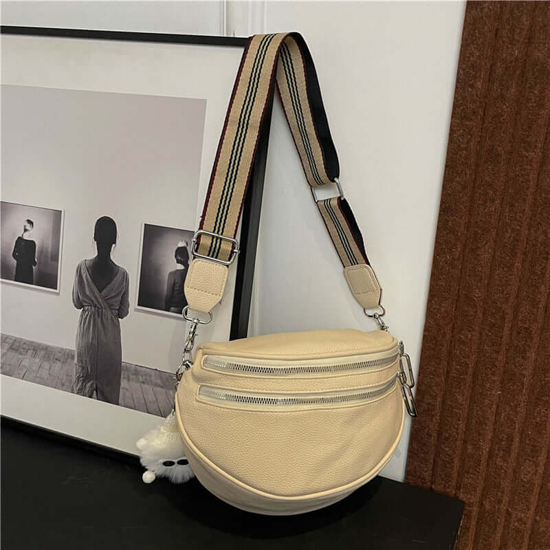 Milky white Ladies Chest Bag with urban simplicity design, featuring a striped adjustable strap, displayed near artistic frames.