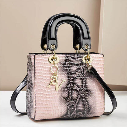 Elegant pink leather handbag with black handles and a gold AV charm, featuring a stylish textured snake pattern design.