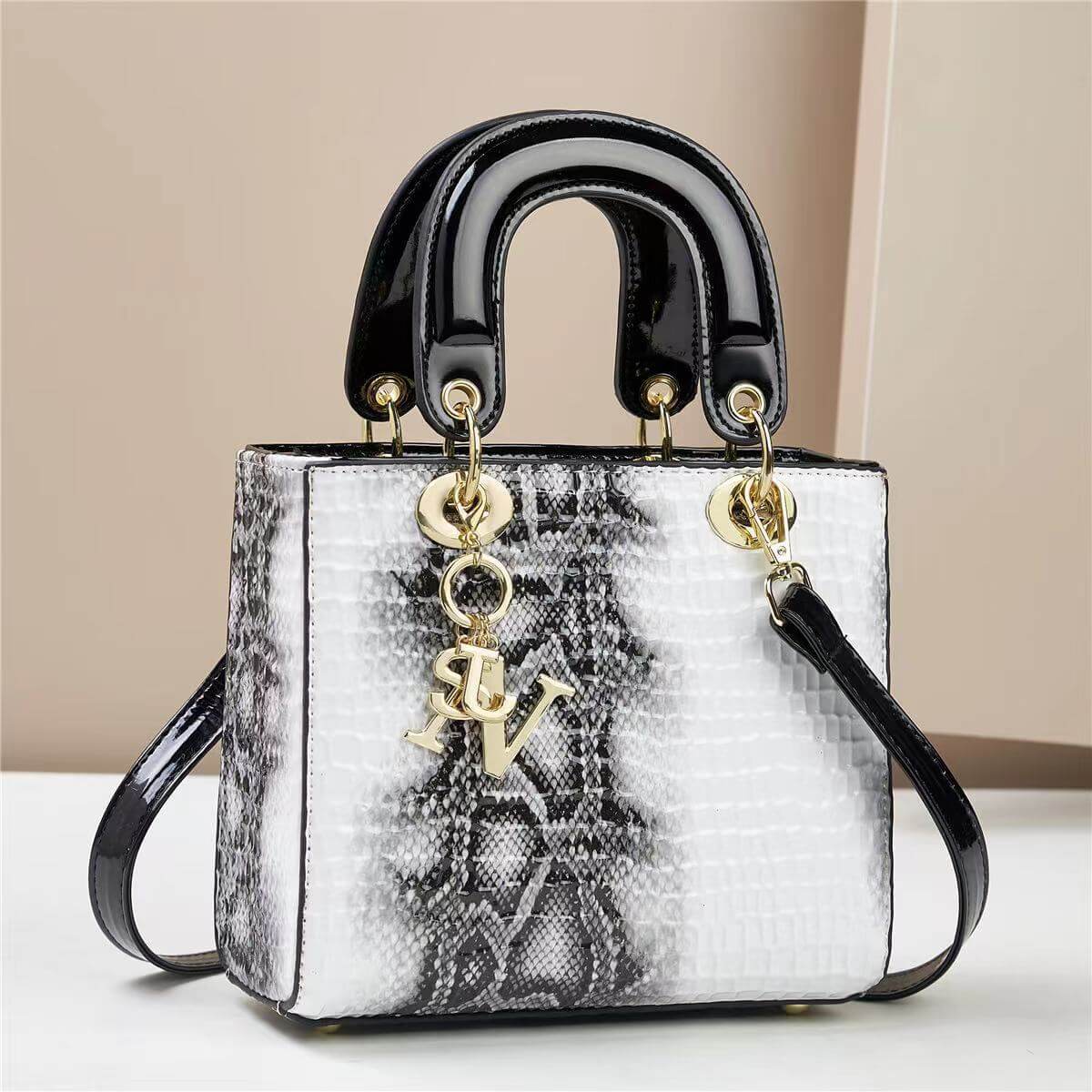 Elegant square handbag with a black handle and snake pattern, featuring gold accents and a letter charm.