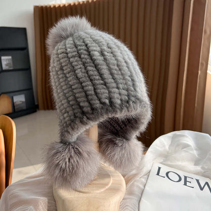 Stylish gray Ear Muffs Hat with delicate fur pom poms, perfect for winter warmth and fashion.