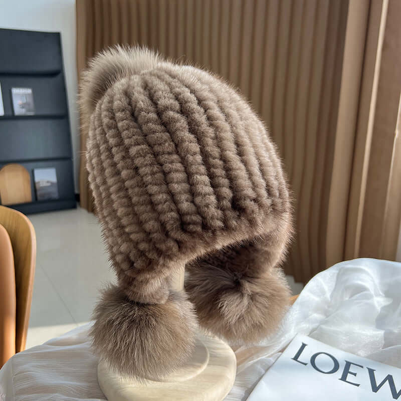 Trendy Ear Muffs Hat in soft brown, featuring earmuffs and pom poms for stylish winter warmth.