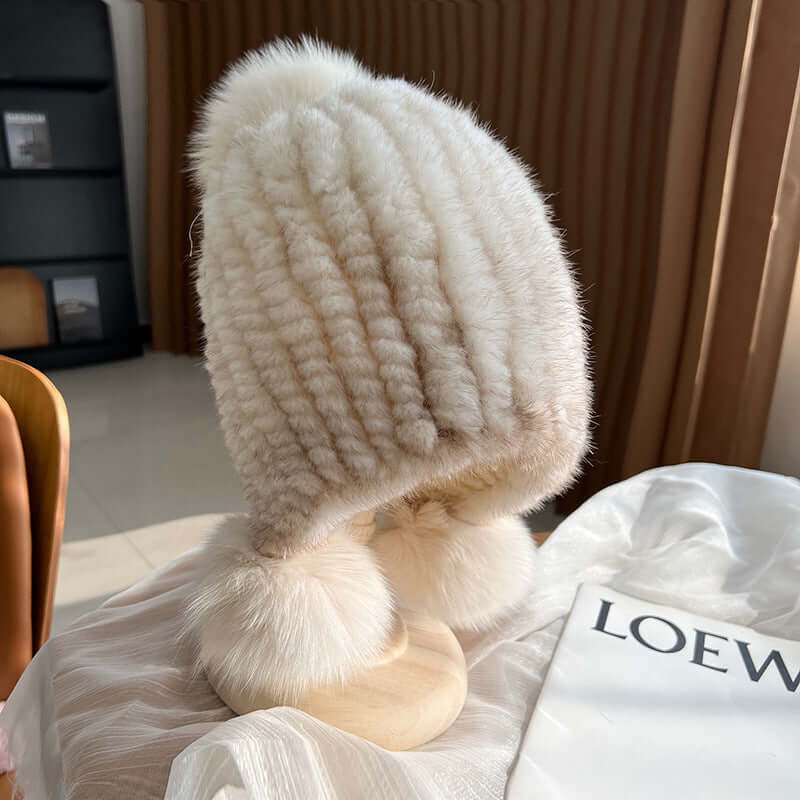 Stylish white Ear Muffs Hat with fluffy pom-poms, perfect for staying warm and trendy in winter.