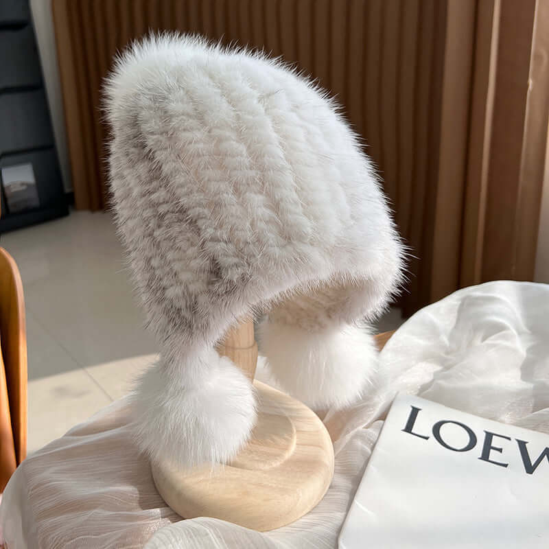 Stylish white Ear Muffs Hat featuring fur texture and pom poms, perfect for winter warmth and fashion.