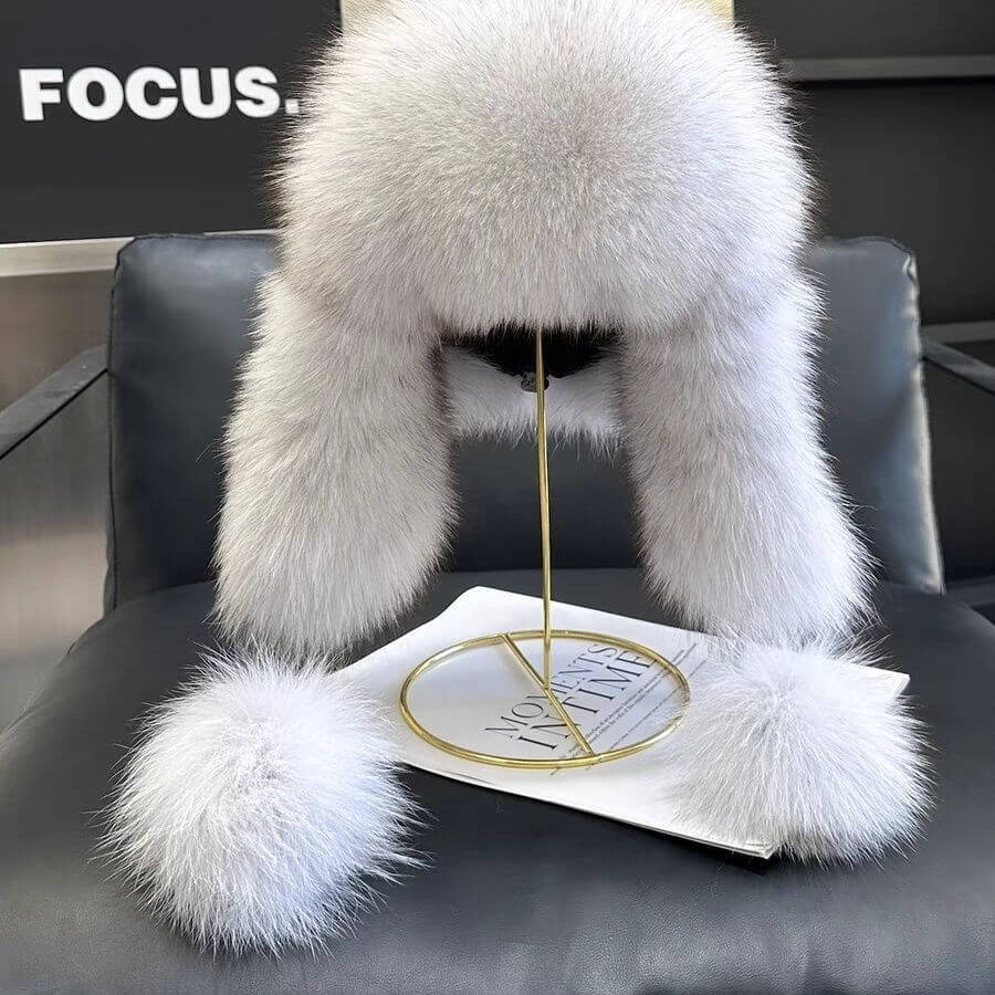 Stylish Ushanka Fur Hat displayed on a stand, featuring fluffy ear flaps and a chic gray color, perfect for winter elegance.