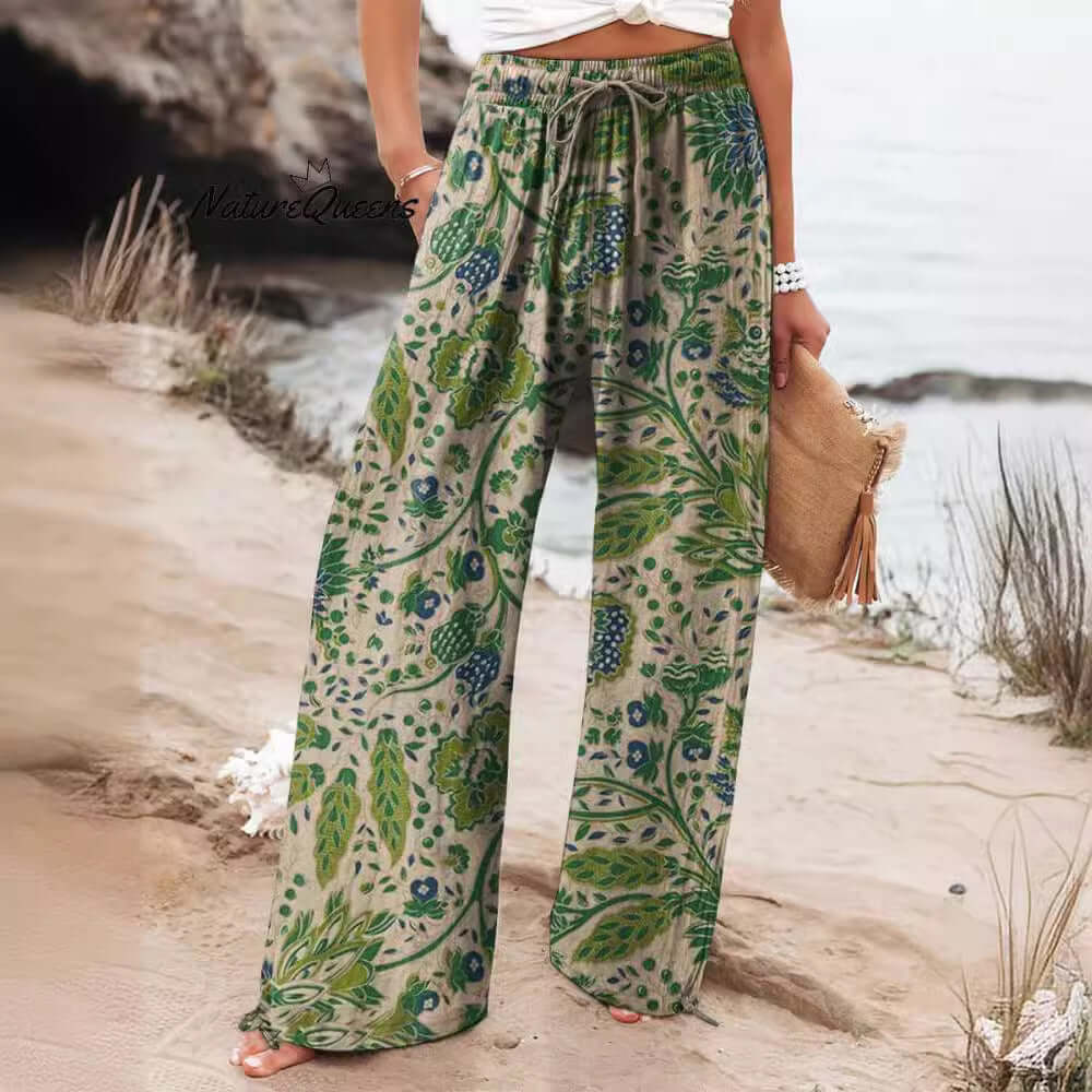 Woman wearing floral wide-leg trousers on beach, made from brushed milk silk fabric with spandex. Available in multiple sizes.