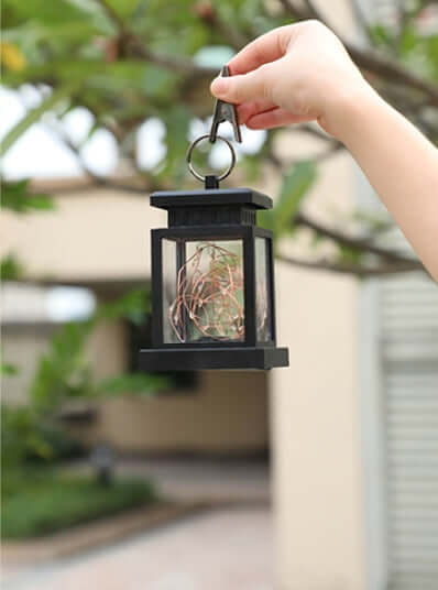 Hand holding stylish Wind Up Lantern outdoors, showcasing eco-friendly design for camping and garden illumination.