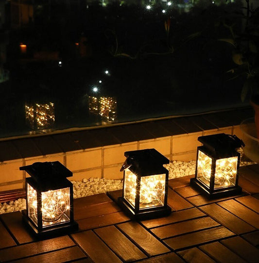 Three wind up lanterns lighting up a wooden deck, ideal for camping or garden retreats with eco-friendly illumination.